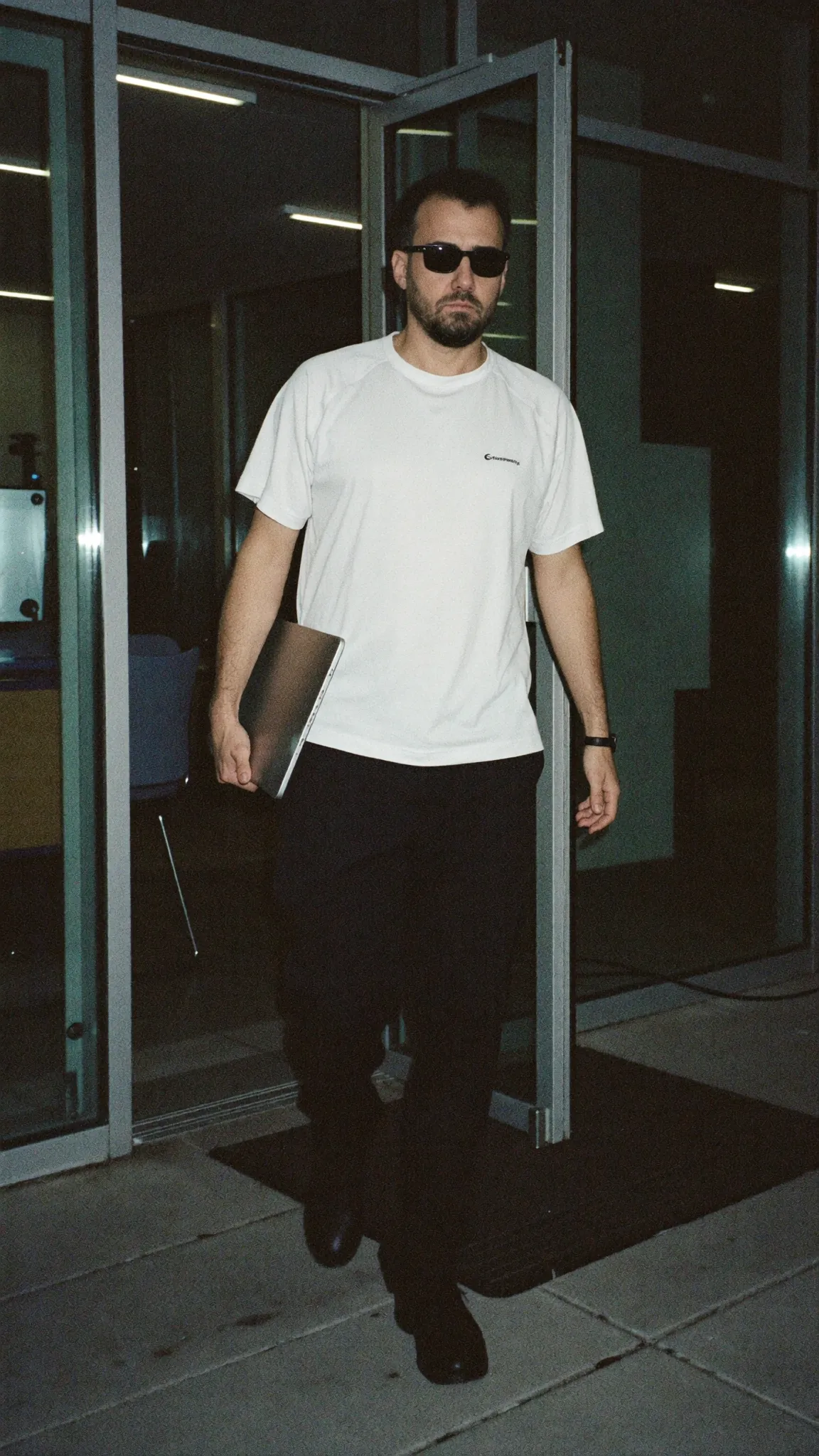 Adolfo Torres saliendo de la oficina de noche, laptop en mano